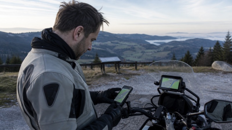 Barevný displej na motorce s navigační mapou a telefon v držáku na řídítkách