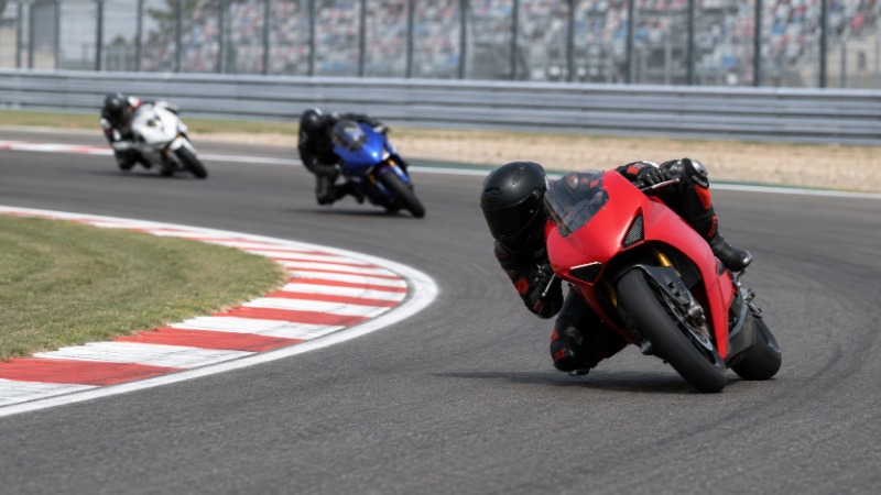 Závodní motocykl MotoGP v hlubokém náklonu projíždí zatáčkou na okruhu