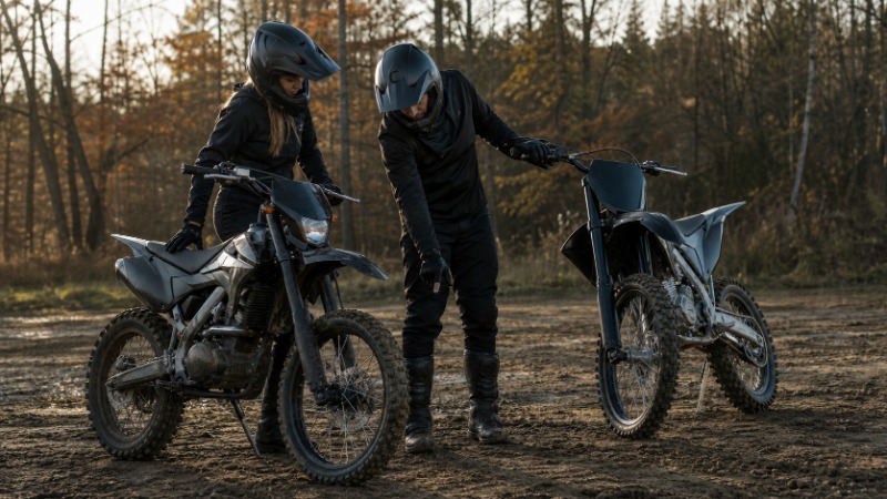 Terénní enduro motorka na nezpevněné lesní cestě, jezdec v přilbě a brýlích