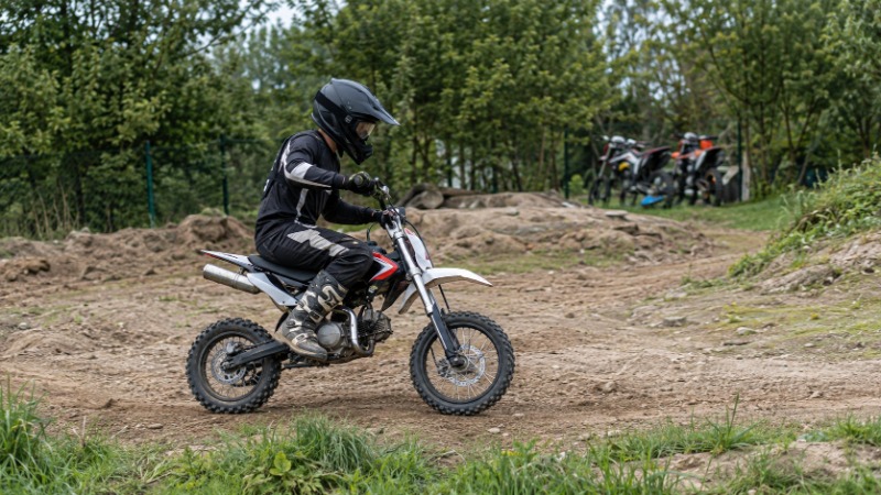 Malá terénní motorka pitbike s nízkým podvozkem a hrubými pneumatikami na hliněné dráze