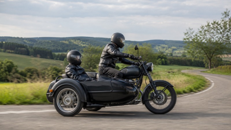 Motocykl s postranním vozíkem (sajdkára) zaparkovaný na ulici, boční pohled na stroj a vozík